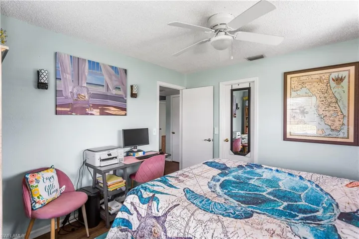 Bedroom featuring ceiling fan, wood-type flooring, and a textured ceiling
