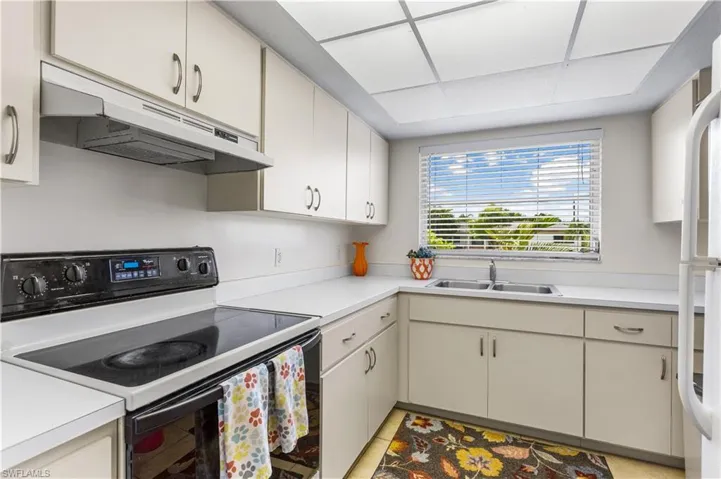 Kitchen with white cabinetry, sink, and electric stove