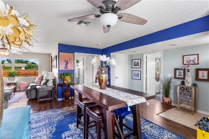 Dining area with a textured ceiling, dark wood-type flooring, and ceiling fan