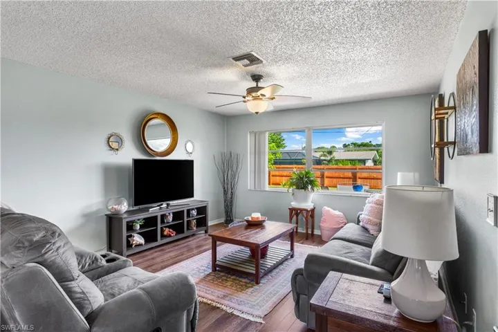 Living room featuring a textured ceiling, wood-type flooring, and ceiling fan