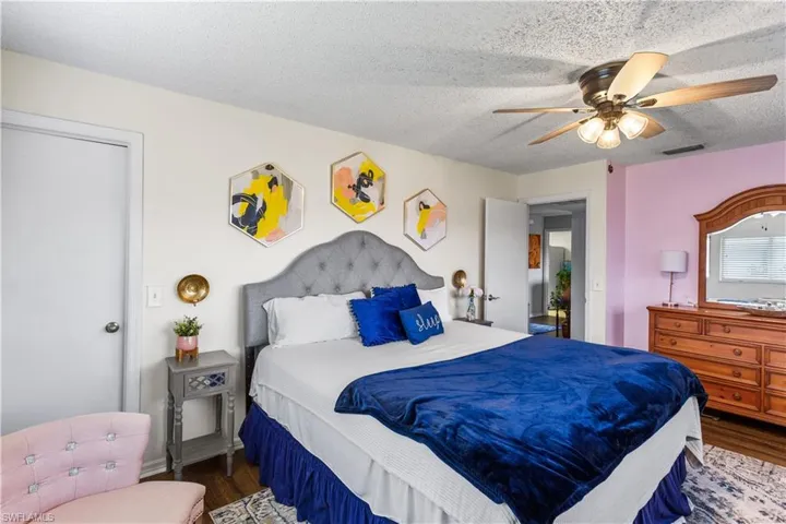 Bedroom featuring ceiling fan, dark hardwood / wood-style floors, and a textured ceiling