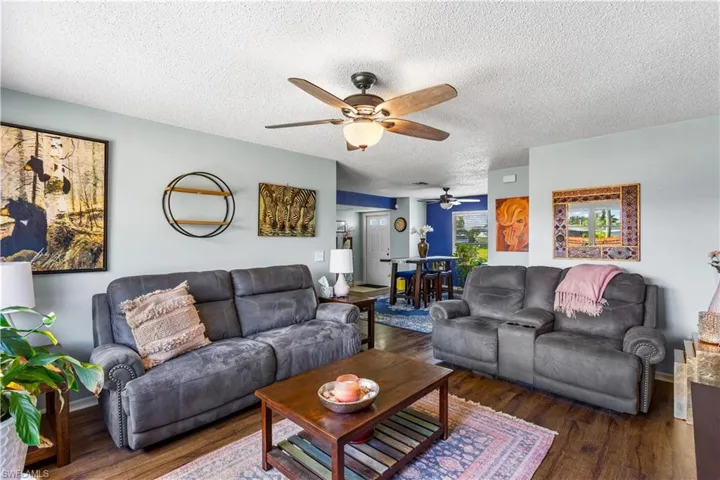 Living room with a textured ceiling, ceiling fan, and dark hardwood / wood-style flooring
