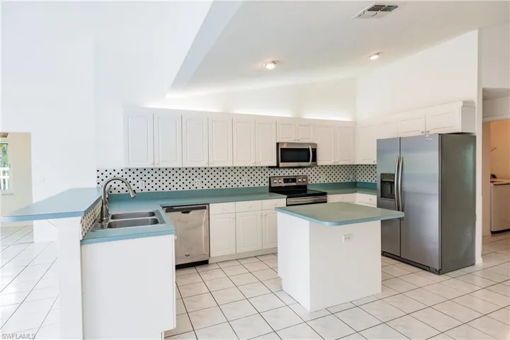 Kitchen featuring tasteful backsplash, stainless steel appliances, sink, kitchen peninsula, and white cabinets