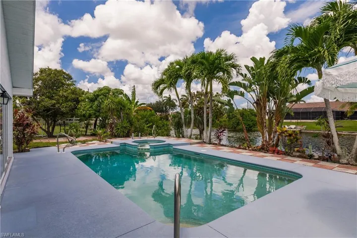 View of pool featuring a water view, a patio area, and an in ground hot tub