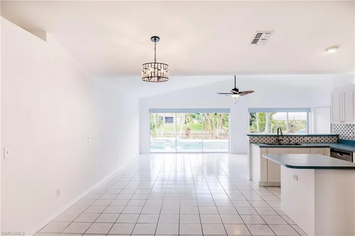 Kitchen with white cabinets, light tile patterned floors, vaulted ceiling, sink, and kitchen peninsula