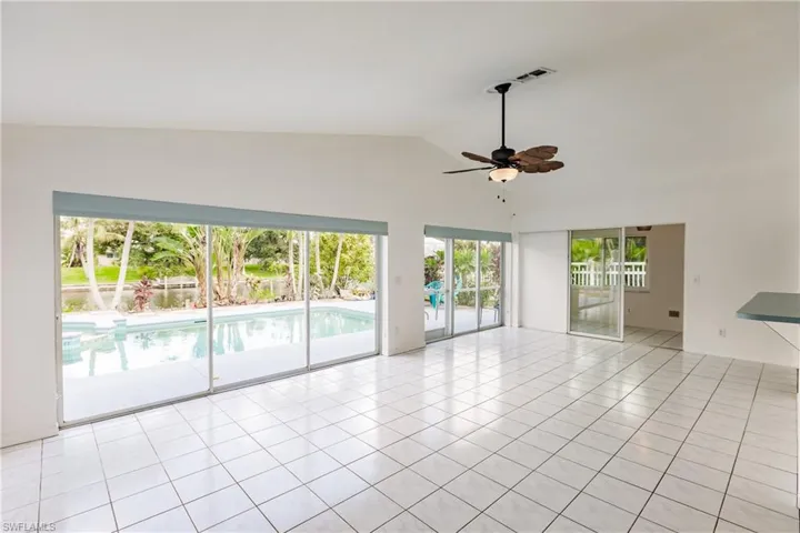 Empty room featuring lofted ceiling, ceiling fan, and light tile patterned floors
