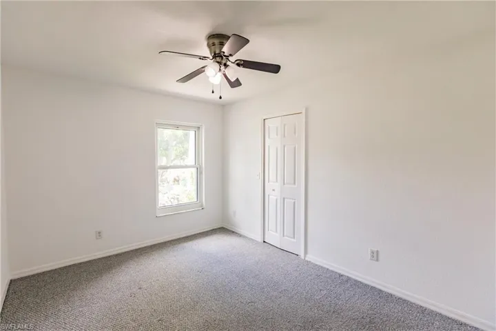 Unfurnished bedroom with ceiling fan, light colored carpet, and a closet