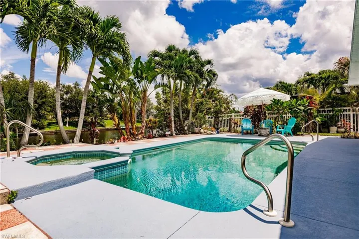 View of swimming pool with a water view, an in ground hot tub, and a patio