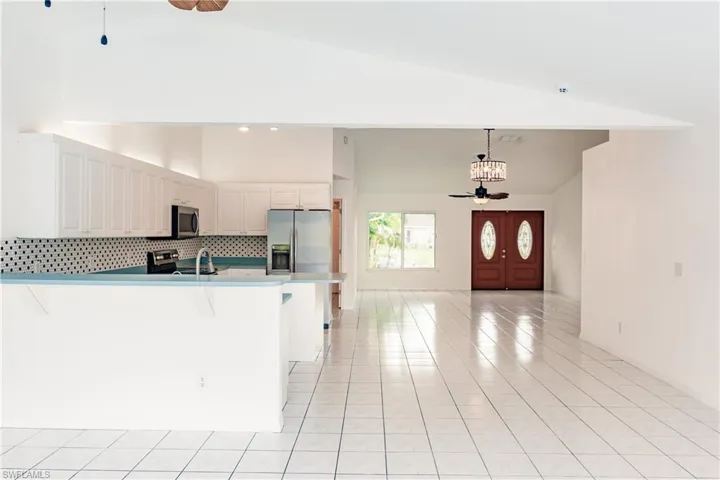 Kitchen with stainless steel appliances, light tile patterned floors, decorative backsplash, and ceiling fan