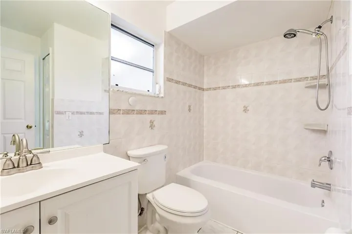 Full bathroom featuring tile walls, toilet, tiled shower / bath combo, and vanity