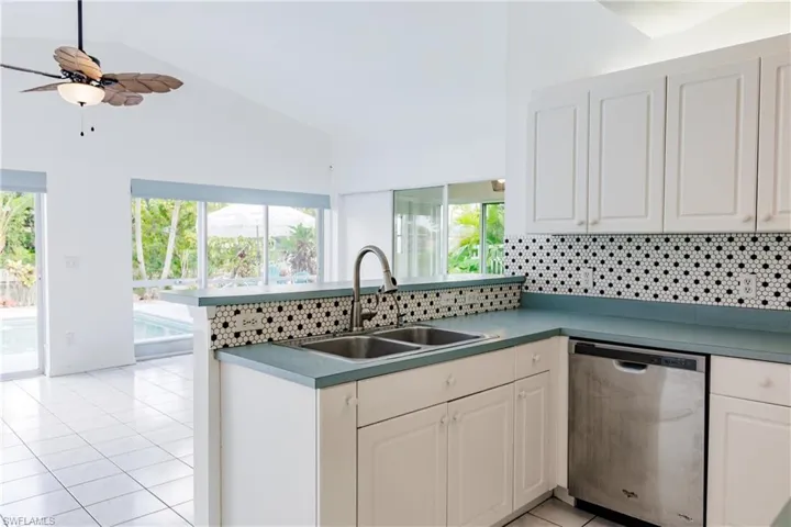 Kitchen featuring backsplash, light tile patterned floors, ceiling fan, vaulted ceiling, and stainless steel dishwasher