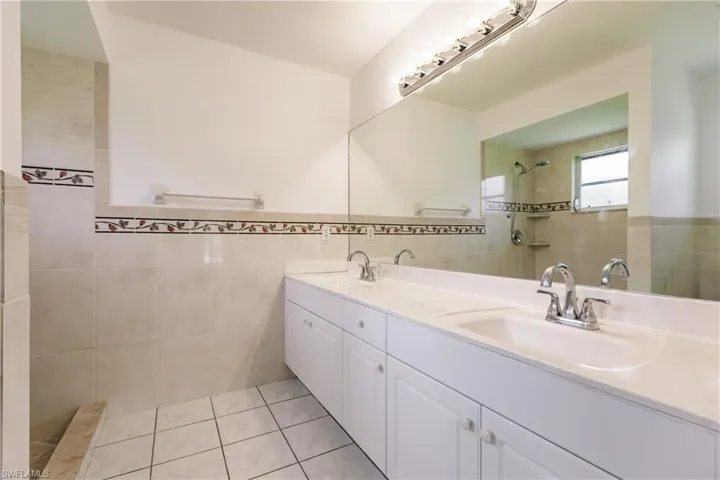 Bathroom featuring vanity, tile walls, a tile shower, and tile patterned flooring