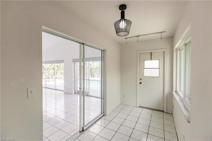Doorway to outside with rail lighting and light tile patterned floors