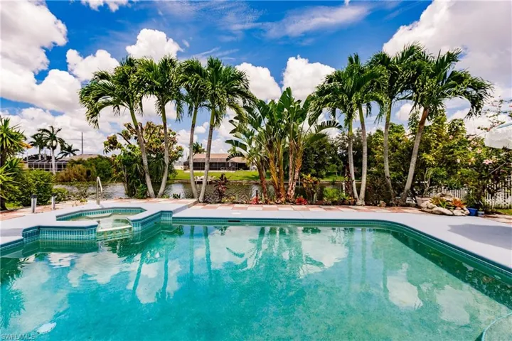 View of swimming pool featuring a water view and an in ground hot tub