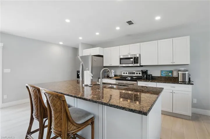 Kitchen with baseboards, visible vents, a sink, a center island with sink, and stainless steel appliances