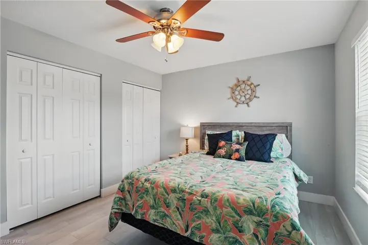 Bedroom featuring ceiling fan, light wood-style flooring, baseboards, and multiple closets