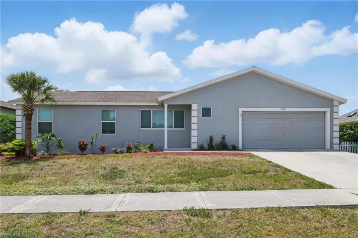 Ranch-style house with an attached garage, concrete driveway, stucco siding, and a front yard