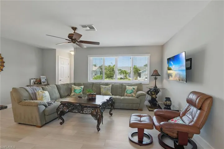 Living room with baseboards, a ceiling fan, visible vents, and light wood-style floors