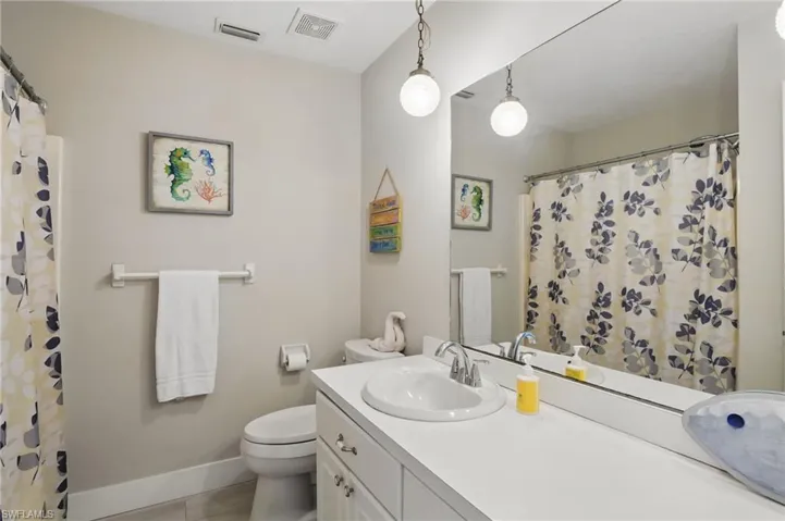 Full bath featuring toilet, baseboards, vanity, and visible vents