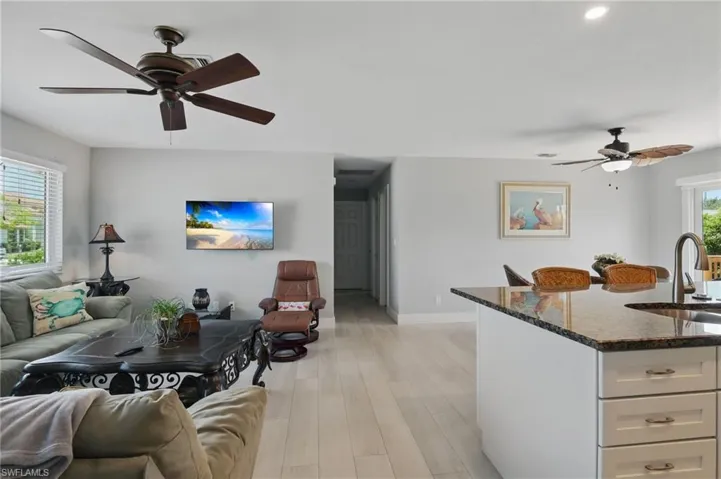 Living area with ceiling fan, baseboards, light wood finished floors, and recessed lighting