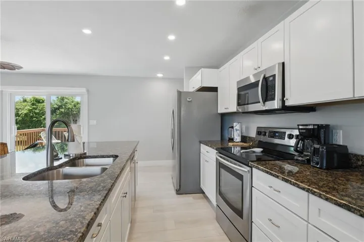 Kitchen featuring recessed lighting, a sink, dark stone counters, white cabinets, and appliances with stainless steel finishes