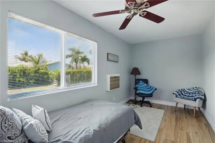 Bedroom featuring multiple windows, a ceiling fan, light wood-style flooring, and baseboards