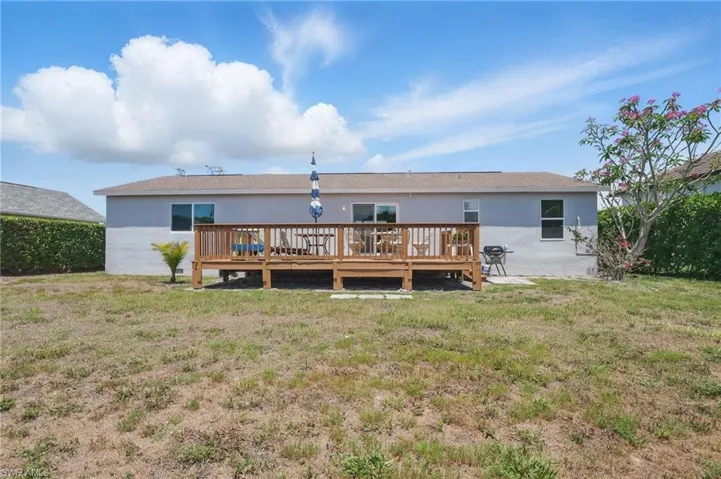 Rear view of property with a yard, stucco siding, and a deck