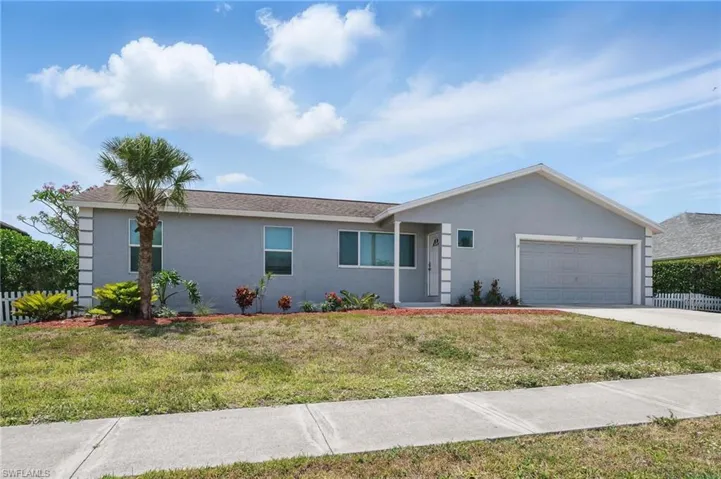 Ranch-style house with concrete driveway, a garage, stucco siding, and a front lawn