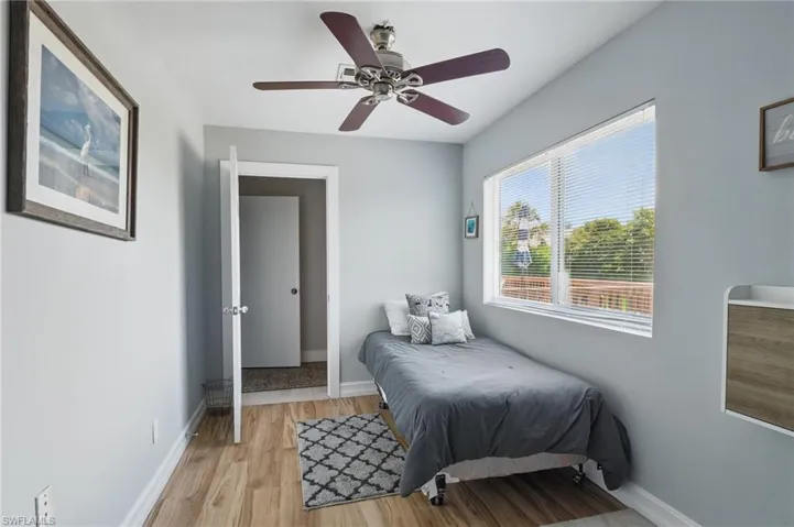 Bedroom with a ceiling fan, light wood-style flooring, and baseboards