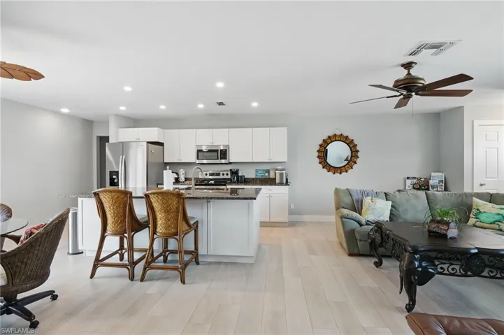 Kitchen with an island with sink, stainless steel appliances, white cabinetry, visible vents, and recessed lighting