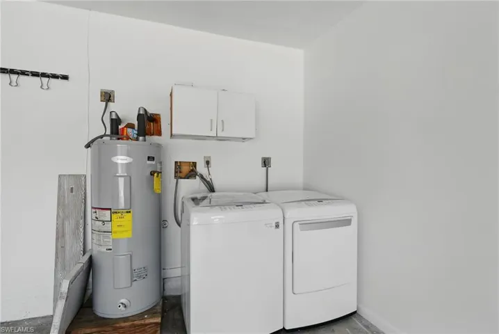 Laundry room with washing machine and clothes dryer, electric water heater, and cabinet space