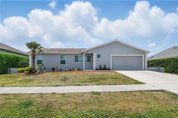 Ranch-style home with driveway, fence, a garage, stucco siding, and a front lawn