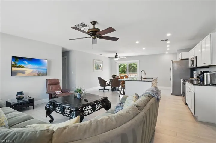 Living room with light wood-type flooring, visible vents, a ceiling fan, and recessed lighting
