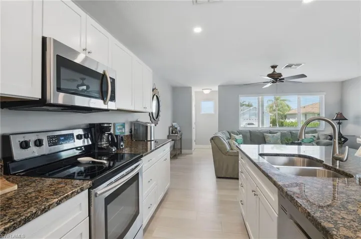 Kitchen with a sink, stainless steel appliances, white cabinetry, visible vents, and light wood-style floors