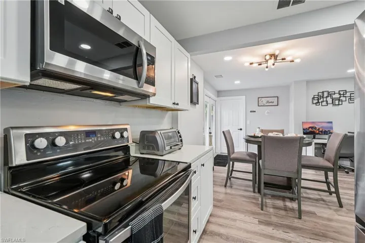 Kitchen featuring stainless steel appliances, white cabinetry, light wood-style floors, recessed lighting, and light stone counters