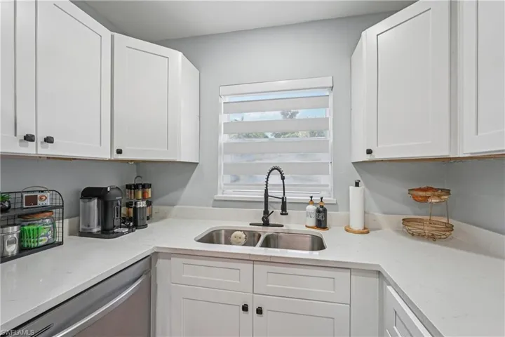 Kitchen with white cabinets, light stone countertops, and dishwasher