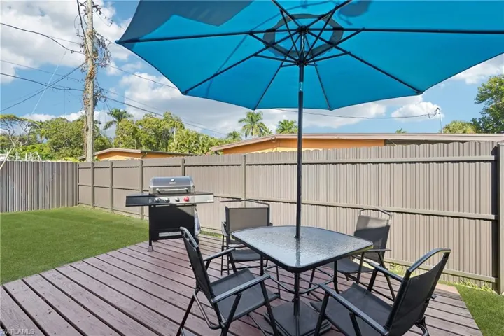 Wooden terrace featuring outdoor dining area, area for grilling, and a fenced backyard