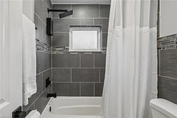 Full bath featuring toilet and shower / bathtub combination with curtain