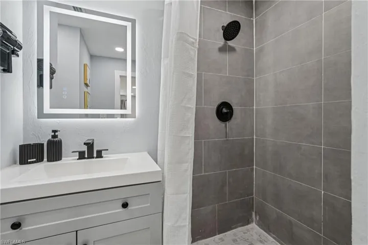 Full bath with a stall shower, vanity, and a textured wall
