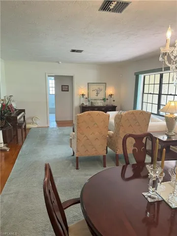 Living room featuring a textured ceiling, hardwood / wood-style flooring, and a chandelier