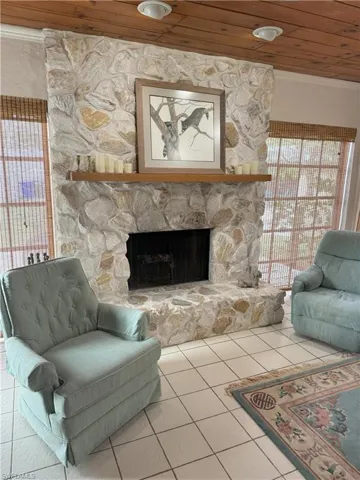 Tiled living room featuring a stone fireplace and wooden ceiling