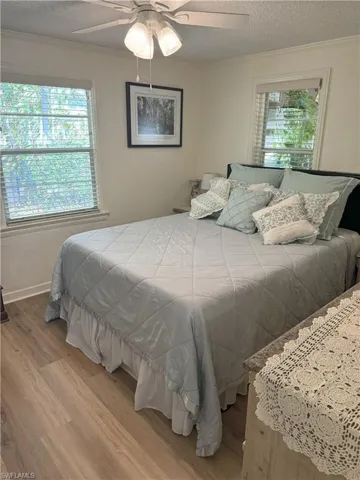 Bedroom with ceiling fan, crown molding, a textured ceiling, and light hardwood / wood-style flooring
