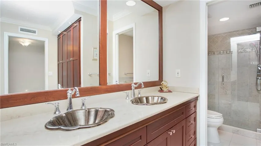 Bathroom with vanity, tile patterned floors, toilet, ornamental molding, and a shower with shower door