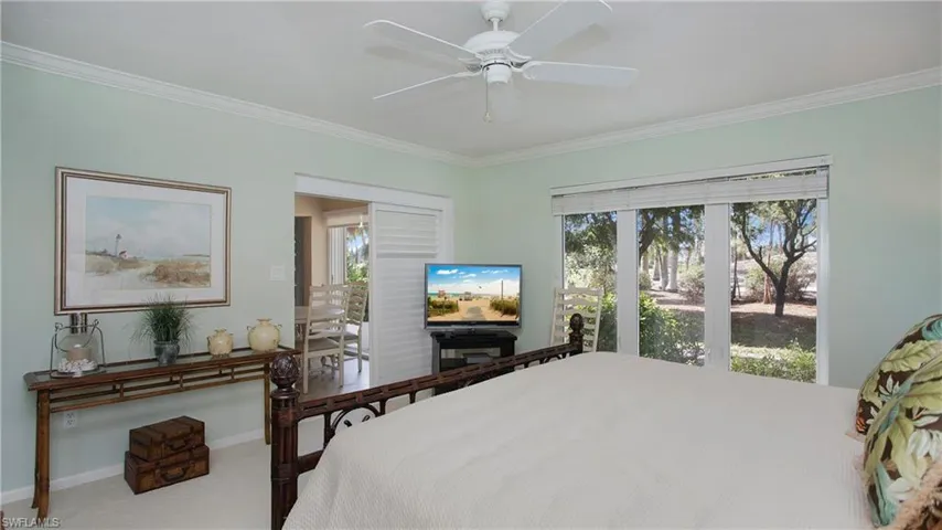 Carpeted bedroom with ceiling fan and crown molding