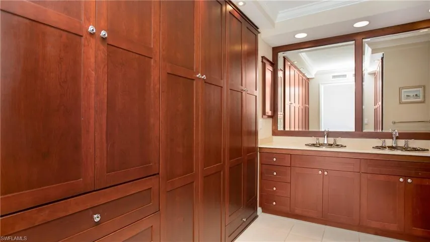 Bathroom featuring tile patterned flooring, vanity, and custom closets and storage