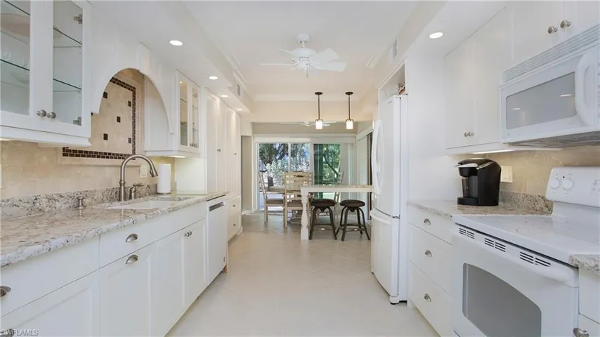 Kitchen featuring white cabinetry, white appliances, sink, and ornamental molding