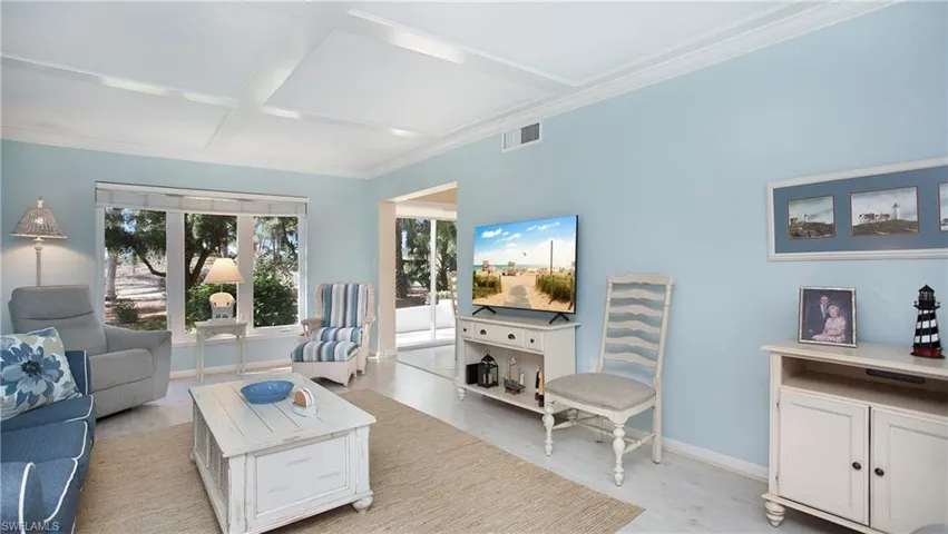 Living room featuring light hardwood / wood-style floors, crown molding, and coffered ceiling