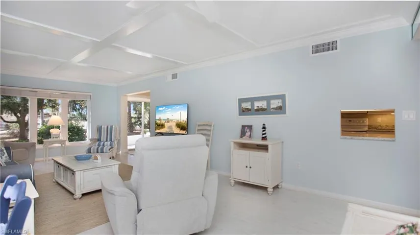 Living room with beam ceiling, light wood-type flooring, crown molding, and coffered ceiling