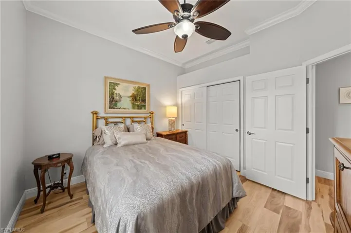 Bedroom with crown molding, a closet, light wood-style floors, baseboards, and a ceiling fan