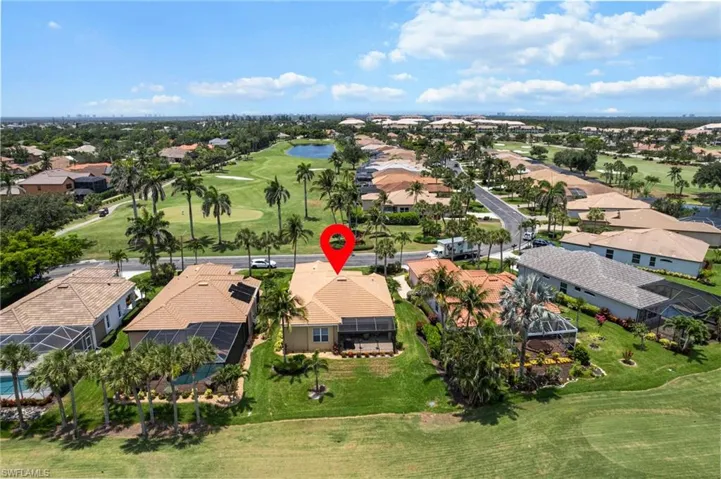 Aerial perspective of suburban area featuring a local golf course and a nearby body of water